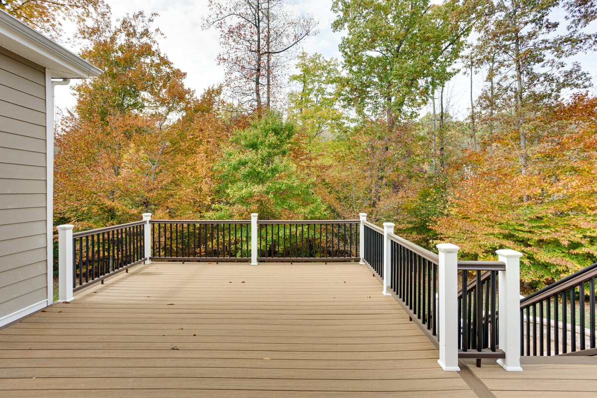 Spacious wooden deck with railing overlooking a vibrant autumn forest